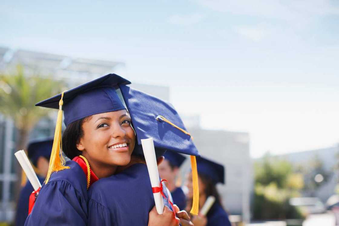 Smiling graduates hugging outdoors