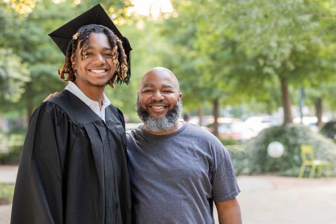 A young black man and his father pose for a family photo at a graduation celebration