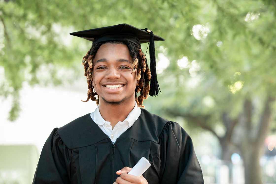 A man smiles for the camera at his graduation.