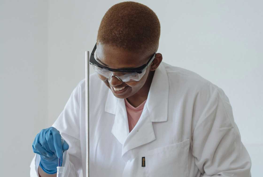 A smiling scientist examining chemical liquid in a modern lab